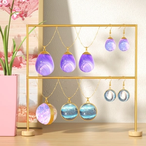 Close-up of galaxy resin pendants in sphere and teardrop shapes on gold display stand