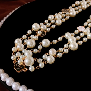 Detail of camellia flower pendants on multi-layer pearl necklace with gold chain