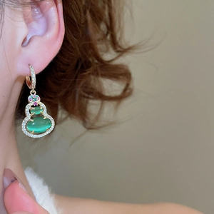 Macro view of 14k gold-plated wulu earrings with green stones and sparkling diamonds