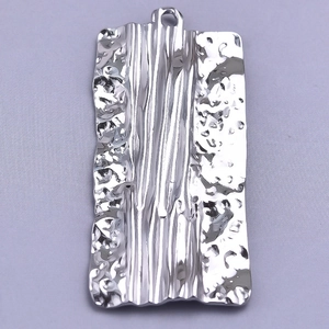 Macro shot of silver stainless steel pendant with organic hammered metal texture