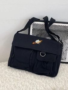Black canvas messenger bag with saturn embroidery and multiple pockets on soft white fur