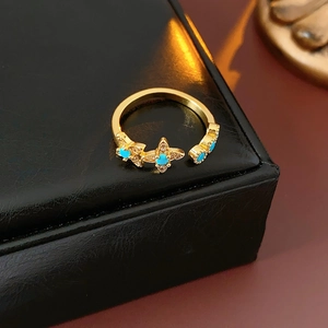 Gros plan d'une bague fleur dorée avec pétales turquoise sur un écrin à bijoux