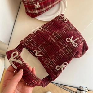 Detail of red plaid tweed handbag featuring 3D white bow embroidery and soft texture
