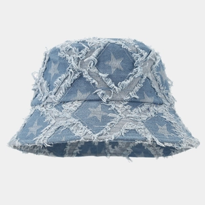 Détail des bords effilochés et des motifs d'étoiles sur le chapeau bob en jean bleu