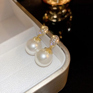 Macro shot of gold plated teardrop earrings with crystals and large white pearls