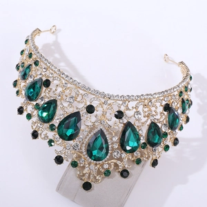 Detail of baroque gold crown featuring emerald green drops and black crystal accents