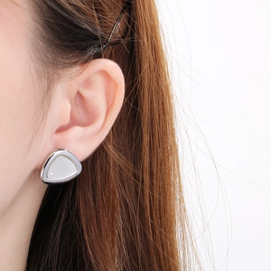 Macro detail of triangle shell earrings with zircon accents on a silver stainless steel base