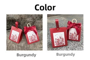 Detail of wine red wedding favor boxes with leather handles and floral illustrations