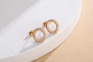 Detailed macro view of rose gold round textured geometric stud earrings on a white stand