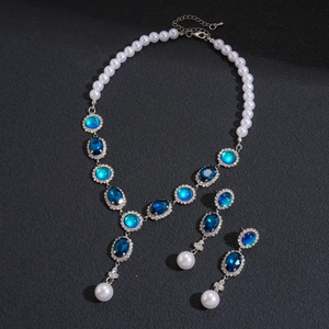 Detailed view of silver necklace and earrings set with blue gems and white pearls