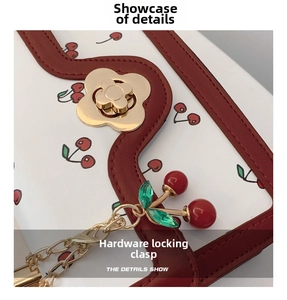 Close-up of golden petal lock and cherry charm on cherry print white faux leather bag