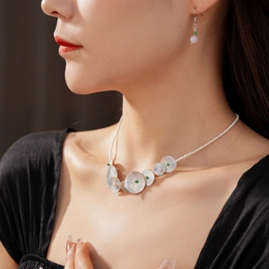 Detail of beaded shell necklace and matching pink crystal earrings on model