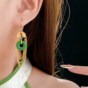 Detailed close-up of a long tassel earring with red gemstone and green jade ring