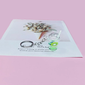 Close-up of a kiwi fruit milk tea cup keychain with green liquid and shiny sequins inside