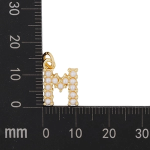 Detailed size reference of a gold M-letter pendant with pearls next to a metric ruler