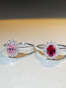 Macro shot of silver rings featuring oval pink and ruby gemstones with halo diamond settings