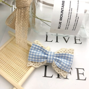 Blue plaid fabric and beige lace bow hair accessory displayed on a rustic bamboo mat