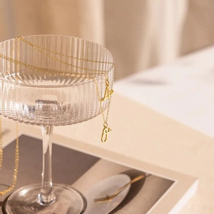 Elegant gold letter A and J pendant necklaces on a glass edge with soft lighting