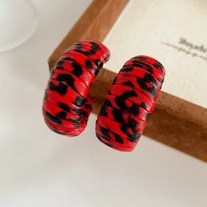 Macro shot of red leopard print leather C-shaped earrings showing premium texture