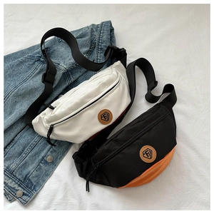 Detail view of Oxford cloth chest bags in off-white and black-orange with leather logo