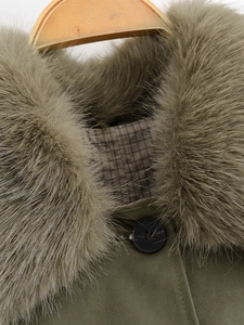 Close-up of winter coat featuring a fluffy faux fur collar and plaid lining detail