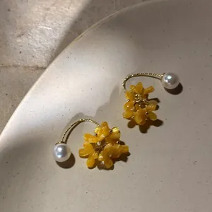 Macro d'une boucle d'oreille fleur en résine et perle blanche sur céramique