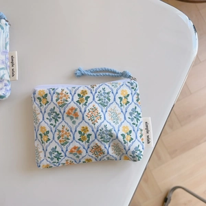 Close-up of floral cotton pouch with blue zipper pull and a simple wish woven label