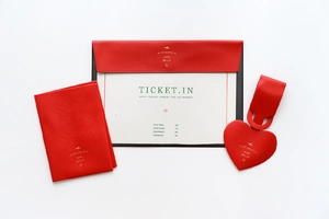 Flat lay of red faux leather travel set including passport holder and heart luggage tag
