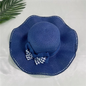 Dettaglio di un cappello di paglia a tesa larga con nastro blu e fiocco a quadri