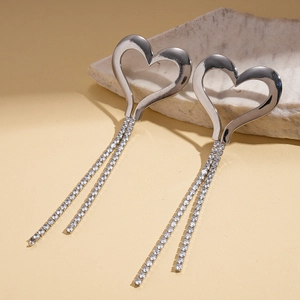 Detailed close-up of silver heart earrings with sparkling rhinestone fringe on stones