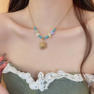 Detail of sun pendant necklace with turquoise beads and colorful stones on model