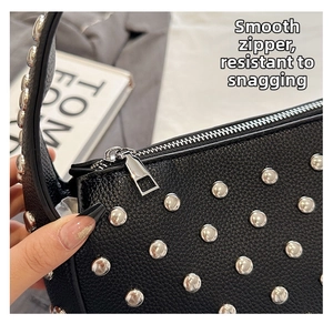 Detail of silver rivets and smooth zipper on a black leather punk style shoulder bag