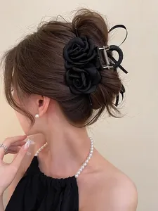 Detail of elegant black fabric rose hair claw clip styled on a model's classic updo