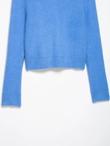 Detail shot of the blue knitted sweater fabric showing soft wool texture and ribbed hem