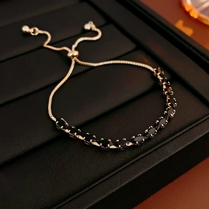 Detail of adjustable gold bracelet with black marquise cut stones on leather tray
