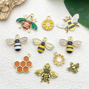 Detail of bee and daisy alloy charms with enamel finish for DIY jewelry making