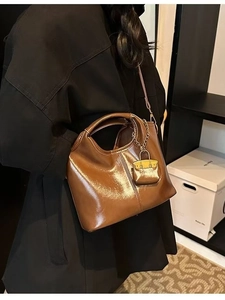 Classic vintage brown oil wax leather tote bag with miniature charm worn by a model