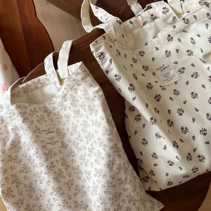 Detailed macro view of floral print cotton tote bags with vintage labels on wooden table