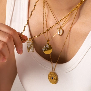 Layered gold necklaces with heart pendant, white shell and evil eye coin charms