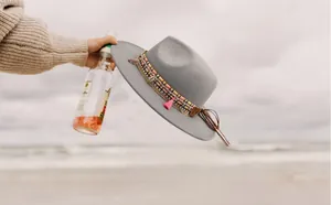 Detail of grey wool fedora hat with boho braided band, shells, and colorful tassels