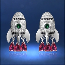 Detail of rocket-shaped earrings with colorful zircon stones and hanging red gems