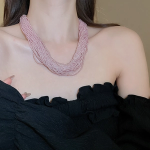 Macro detail of multi-layer pink beaded necklace with elegant pearl-like luster on model