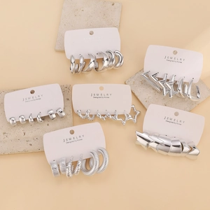 Detailed view of silver C-shape earrings and star-shaped studs on stone display