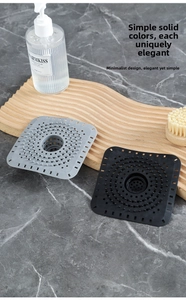 Primo piano di copripiletta quadrati in silicone grigio e nero su vassoio di legno