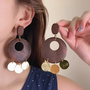 Detailed close-up shot of vintage wood round drop earrings with golden sequin dangles