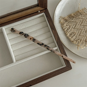 Macro view of leopard print acetate hair claw clip resting in a wooden jewelry box