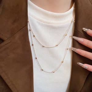 Detail of layered gold beaded necklace on model featuring double-strand minimalist design