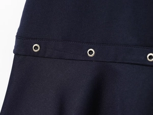 Detail of silver rivets on dark navy twill fabric for an asymmetrical dress design
