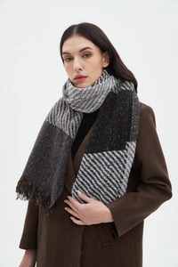 Detail of winter scarf featuring herringbone pattern and tassels on warm wool blend fabric