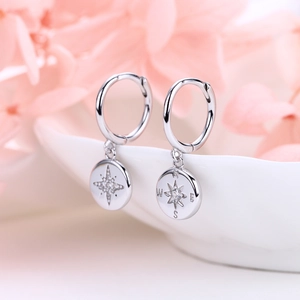 Macro detail of S925 sterling silver compass earrings with zircon and star engraving